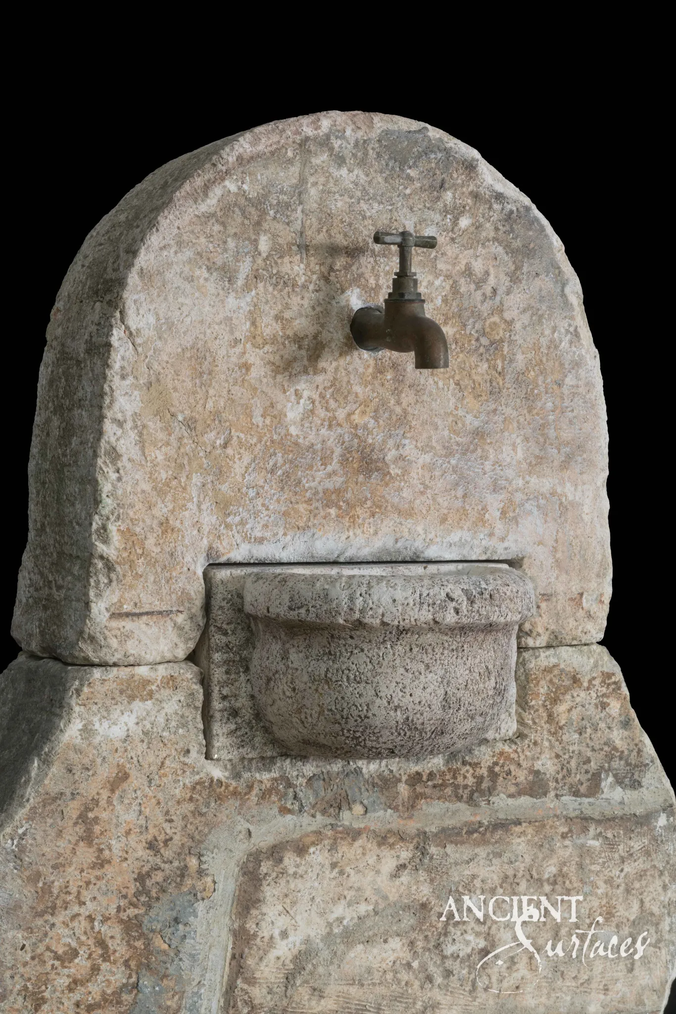 Small reclaimed limestone wall fountain with an antique brass tap over a carved stone cup basin